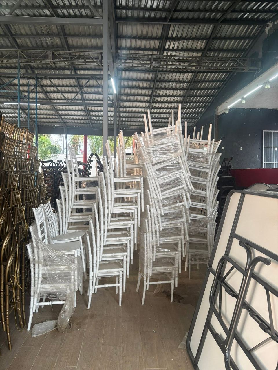 Sillas Tiffany blancas apiladas y protegidas en el almacén de Diversiones Papus
